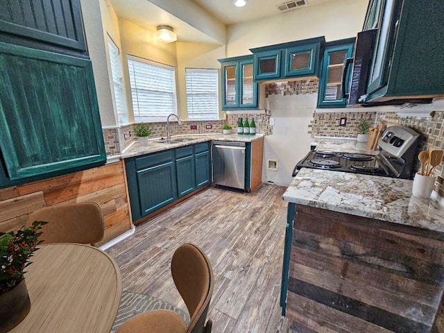 kitchen featuring stainless steel appliances, blue cabinets, tasteful backsplash, and sink