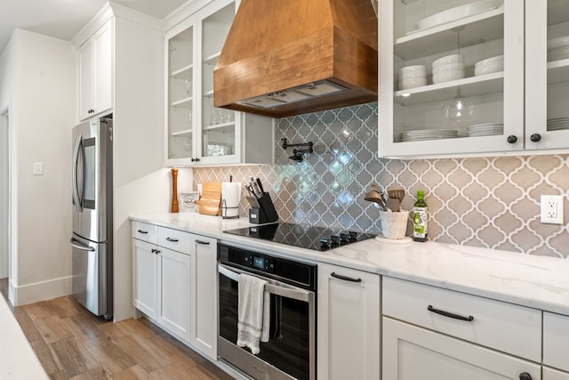 kitchen featuring decorative backsplash, appliances with stainless steel finishes, custom exhaust hood, light hardwood / wood-style flooring, and white cabinetry