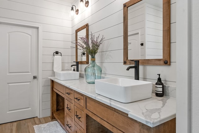 bathroom with vanity, wood walls, and wood-type flooring