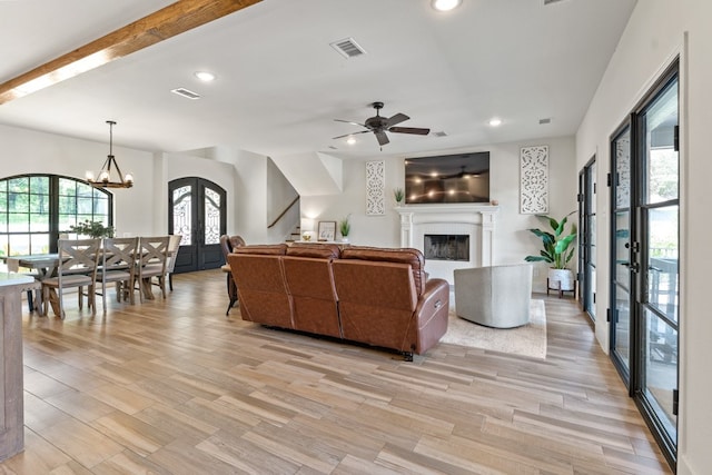 living room with ceiling fan with notable chandelier, light wood-type flooring, and french doors