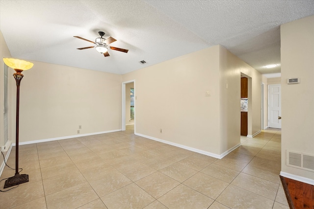 unfurnished room with ceiling fan, light tile patterned floors, and a textured ceiling