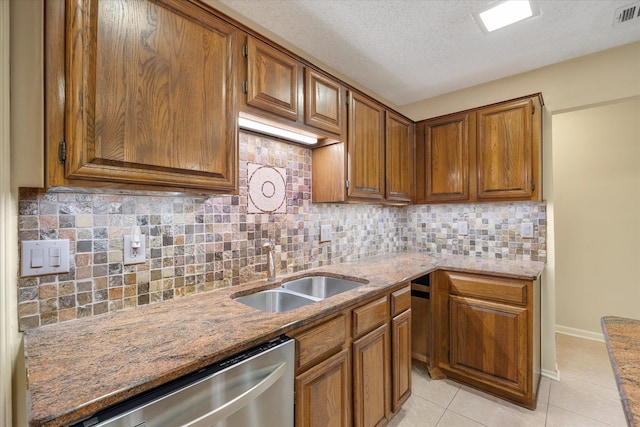 kitchen with sink, stainless steel dishwasher, light tile patterned floors, tasteful backsplash, and light stone counters