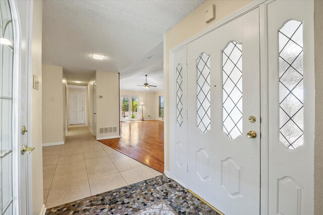 entrance foyer with ceiling fan, light hardwood / wood-style floors, and a textured ceiling