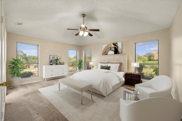 carpeted bedroom featuring multiple windows, ceiling fan, and a textured ceiling