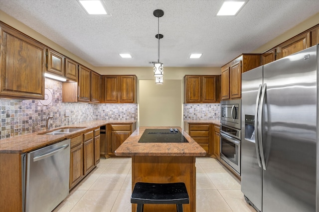 kitchen featuring sink, hanging light fixtures, decorative backsplash, a kitchen island, and appliances with stainless steel finishes