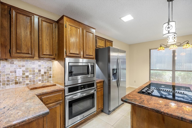 kitchen with hanging light fixtures, appliances with stainless steel finishes, tasteful backsplash, a notable chandelier, and light stone counters