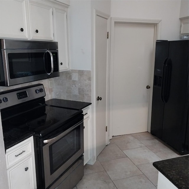 kitchen with white cabinetry, stainless steel appliances, backsplash, dark stone countertops, and light tile patterned flooring