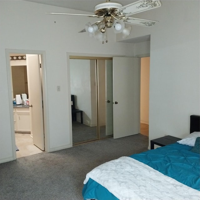 carpeted bedroom with ensuite bath, a closet, and ceiling fan