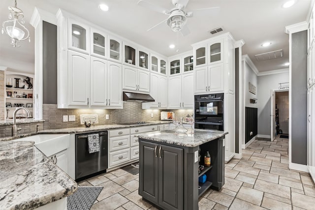 kitchen featuring hanging light fixtures, white cabinets, light stone counters, and black appliances