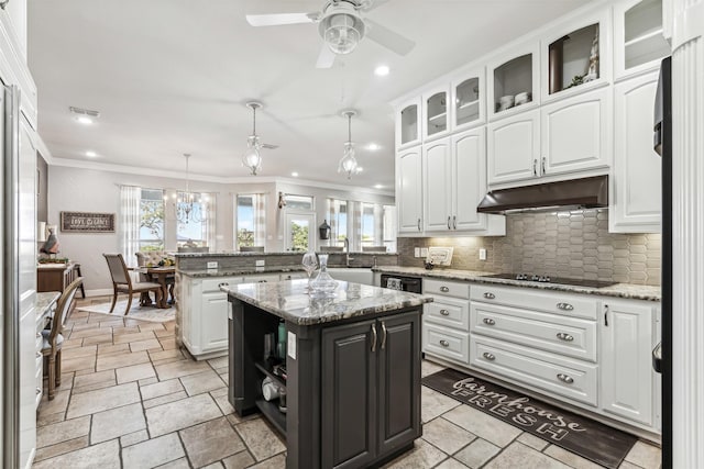 kitchen with a kitchen island, pendant lighting, white cabinets, and light stone counters