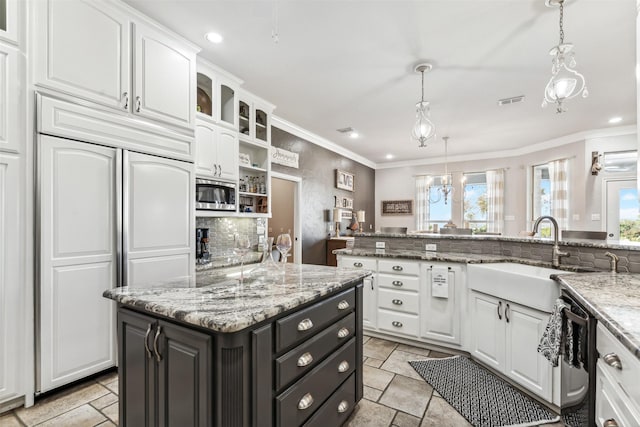 kitchen featuring pendant lighting, white cabinetry, sink, a center island, and built in appliances