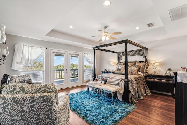 bedroom with a raised ceiling, hardwood / wood-style floors, access to outside, and french doors