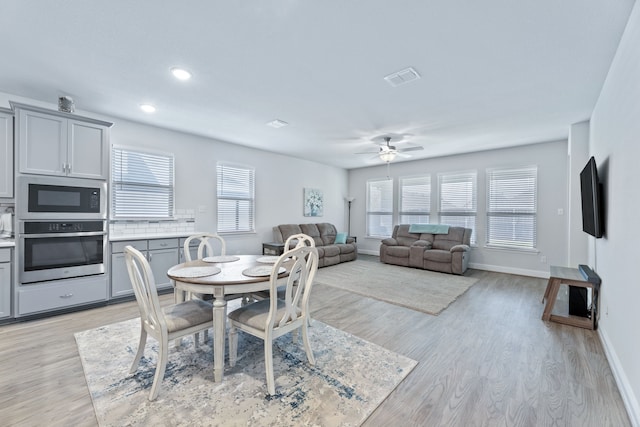 dining room with light wood-type flooring, a wealth of natural light, and ceiling fan