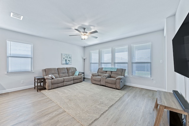 living room featuring ceiling fan, light hardwood / wood-style floors, and a wealth of natural light