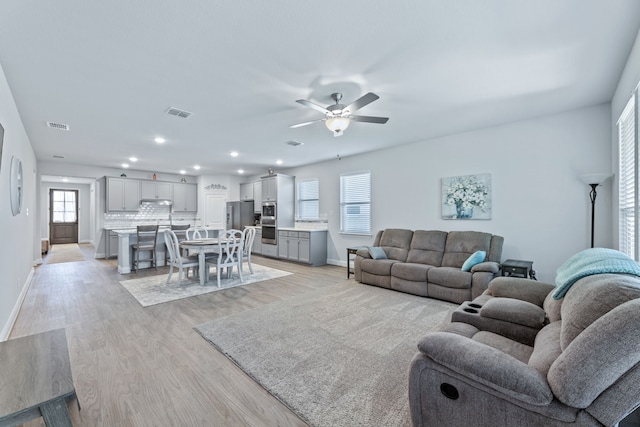 living room with ceiling fan and light hardwood / wood-style flooring