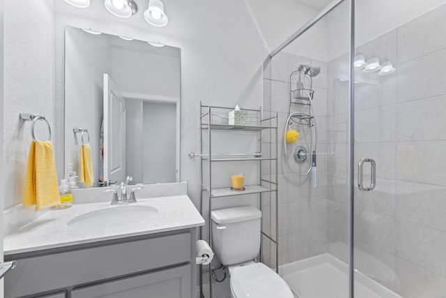 bathroom with vanity, a shower with shower door, and toilet