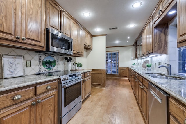 kitchen with light hardwood / wood-style floors, sink, light stone countertops, and stainless steel appliances