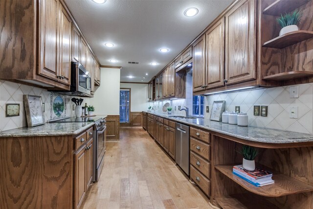 kitchen featuring appliances with stainless steel finishes, light wood-type flooring, backsplash, and sink