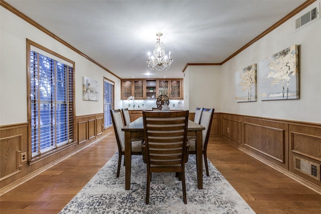 dining space featuring dark wood-type flooring, a chandelier, and ornamental molding