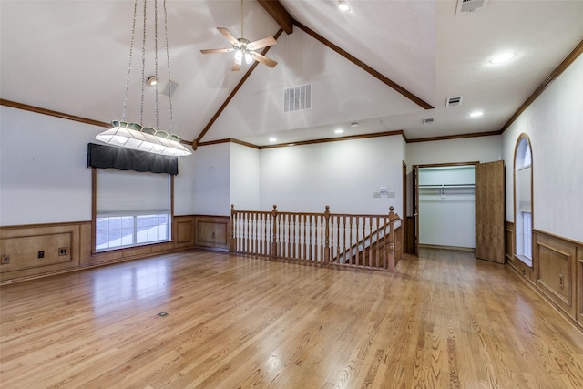 empty room with high vaulted ceiling, light wood-type flooring, ornamental molding, ceiling fan, and beam ceiling