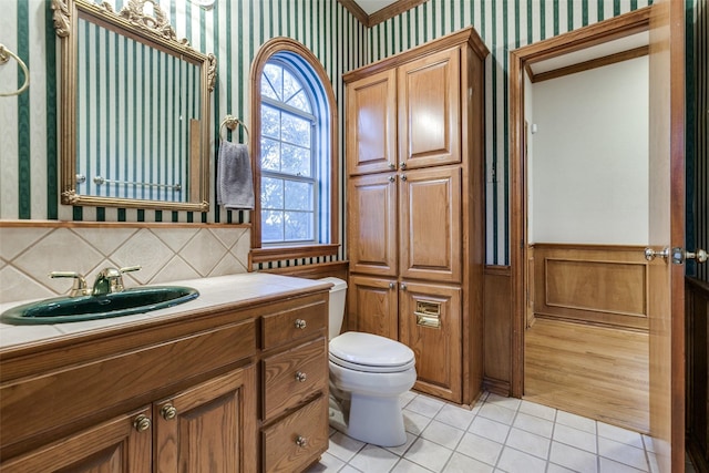 bathroom featuring tasteful backsplash, tile patterned floors, toilet, vanity, and ornamental molding