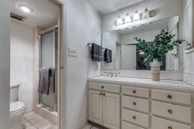 bathroom with tile patterned flooring, vanity, a shower with shower door, and toilet