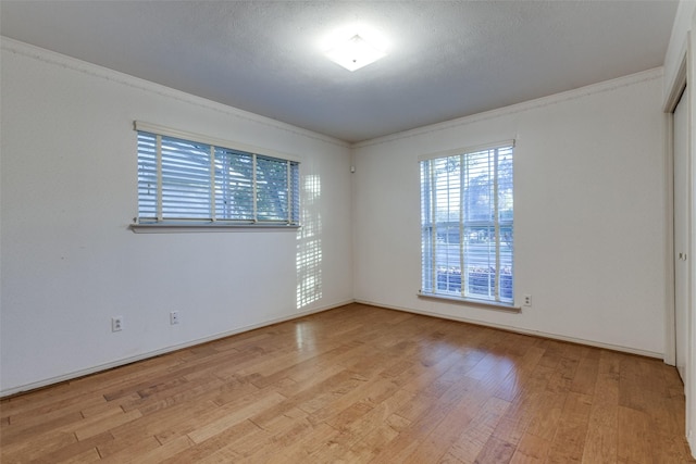 empty room featuring crown molding, light hardwood / wood-style flooring, and a textured ceiling