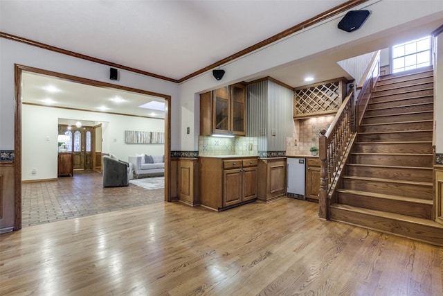 kitchen featuring stainless steel dishwasher, ornamental molding, light hardwood / wood-style floors, and backsplash