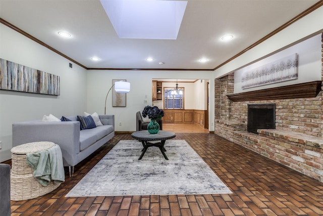 living room featuring crown molding, a brick fireplace, a notable chandelier, and a skylight