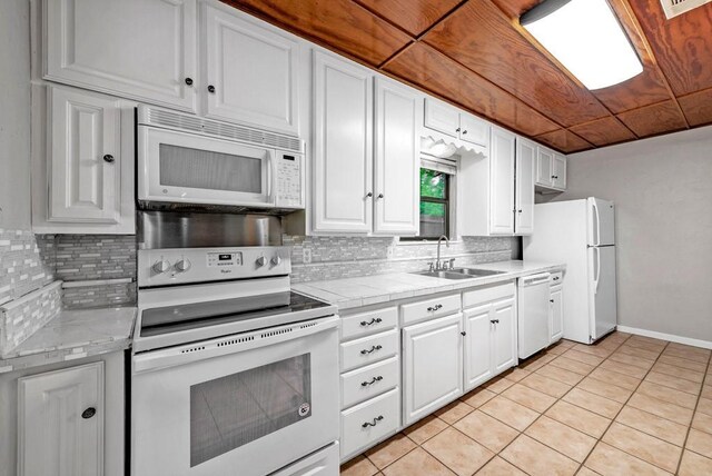 kitchen featuring sink, white appliances, light tile patterned floors, and white cabinets