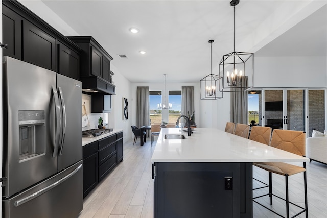 kitchen featuring a kitchen island with sink, sink, a breakfast bar area, and appliances with stainless steel finishes