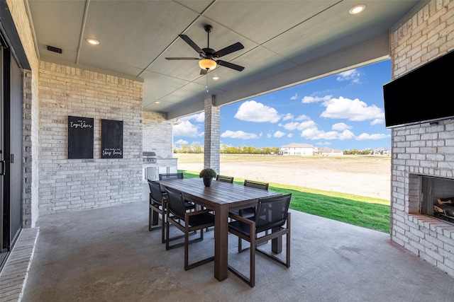 view of patio with an outdoor brick fireplace and ceiling fan