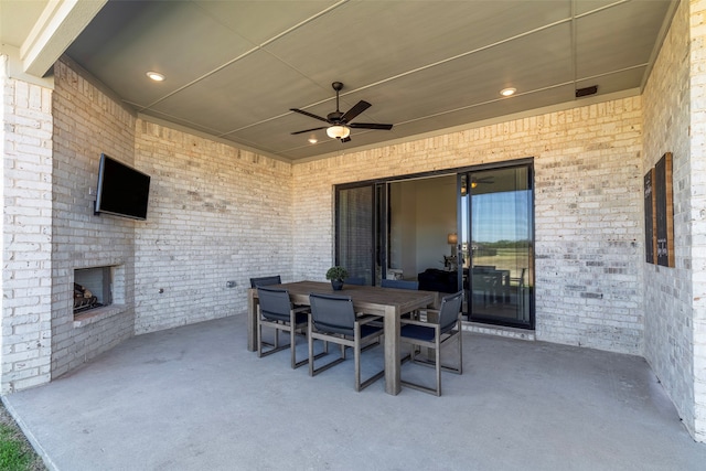 view of patio with an outdoor brick fireplace and ceiling fan