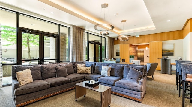 living room featuring light carpet, a raised ceiling, and wood walls