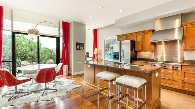 kitchen with stone counters, light hardwood / wood-style floors, a kitchen island with sink, and sink