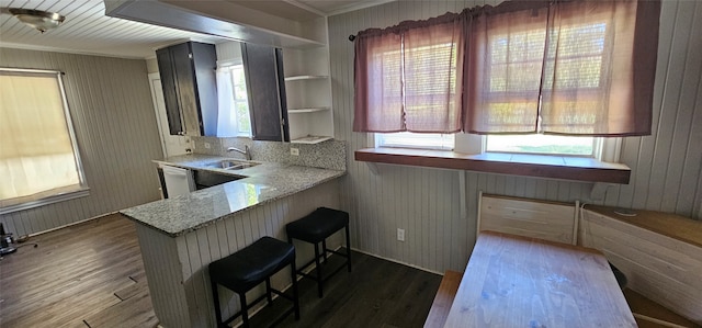 kitchen with plenty of natural light, kitchen peninsula, dark wood-type flooring, and a breakfast bar area