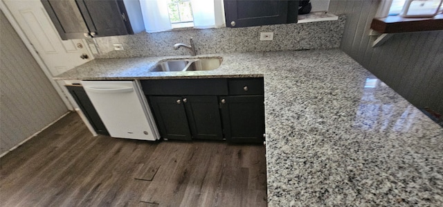 kitchen with sink, dark wood-type flooring, backsplash, white dishwasher, and light stone countertops