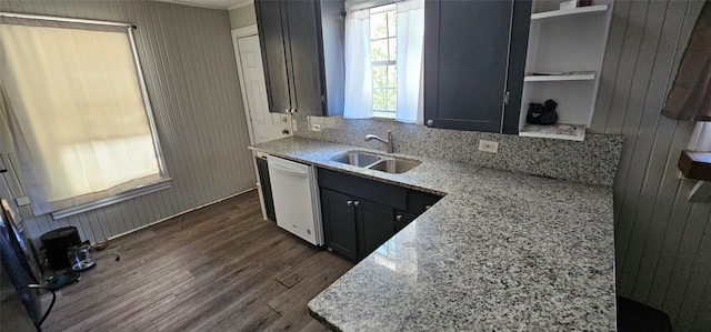 kitchen featuring wooden walls, dishwasher, sink, dark hardwood / wood-style flooring, and light stone countertops