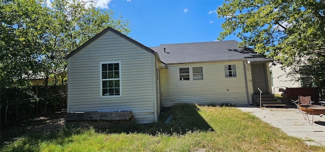 back of property with a yard, a patio area, and an outdoor fire pit