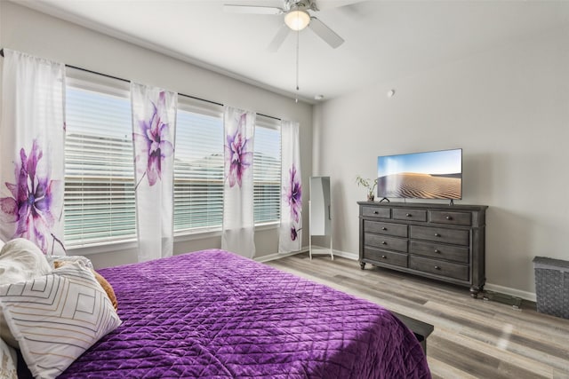 bedroom with light wood-type flooring, multiple windows, and ceiling fan