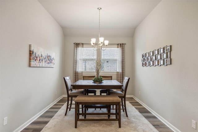 dining area featuring hardwood / wood-style floors, lofted ceiling, and a notable chandelier