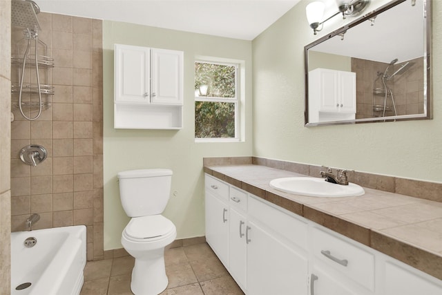 full bathroom featuring tile patterned flooring, vanity, tiled shower / bath, and toilet