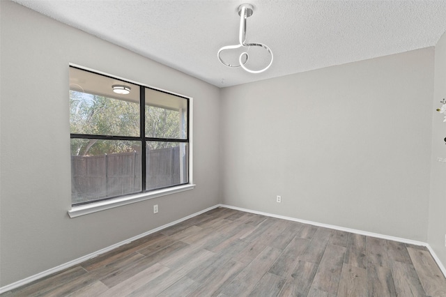 unfurnished room featuring wood-type flooring and a textured ceiling