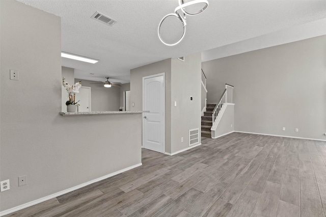 unfurnished living room featuring hardwood / wood-style floors, a textured ceiling, and ceiling fan