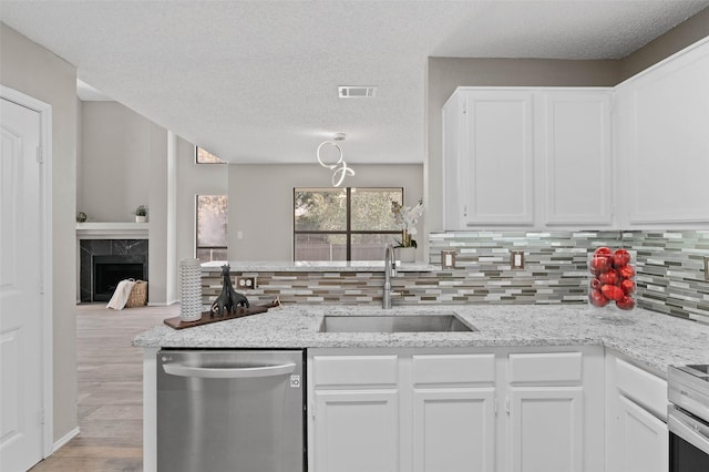 kitchen featuring sink, a premium fireplace, appliances with stainless steel finishes, light stone counters, and white cabinetry