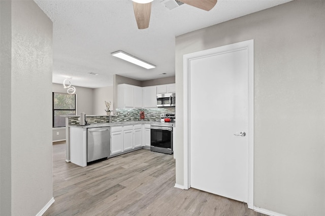 kitchen with kitchen peninsula, white cabinetry, light wood-type flooring, and appliances with stainless steel finishes