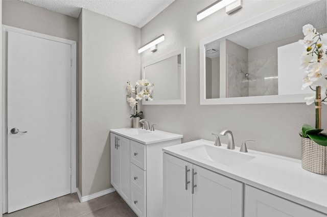 bathroom with a shower, tile patterned flooring, vanity, and a textured ceiling