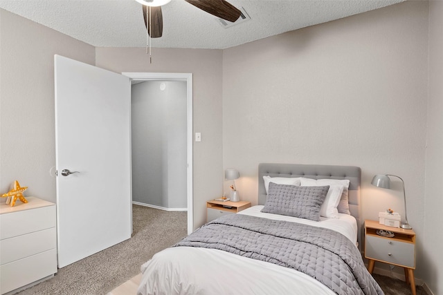 carpeted bedroom featuring ceiling fan and a textured ceiling