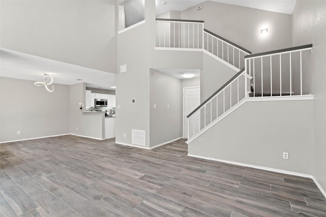 unfurnished living room with wood-type flooring and high vaulted ceiling