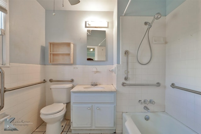 full bathroom with vanity, tiled shower / bath, tile walls, and toilet